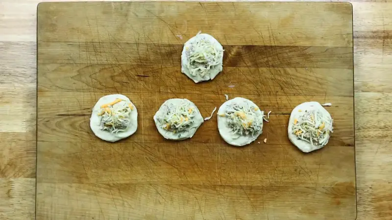 filling tuna and cheese into biscuit dough