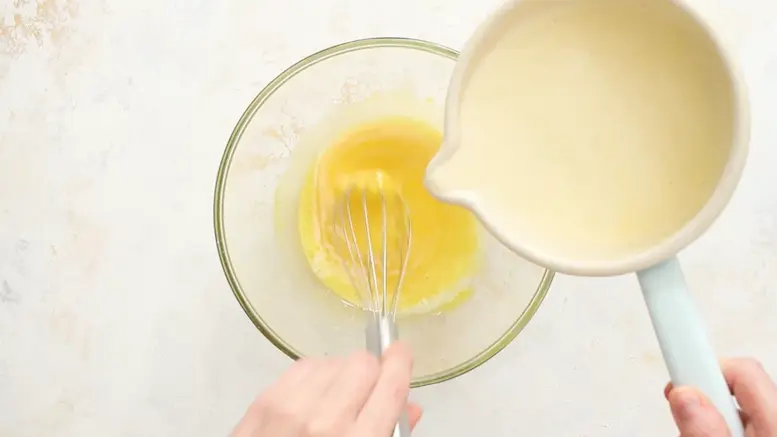 mixing yolks and heavy cream to make Creme Brulee